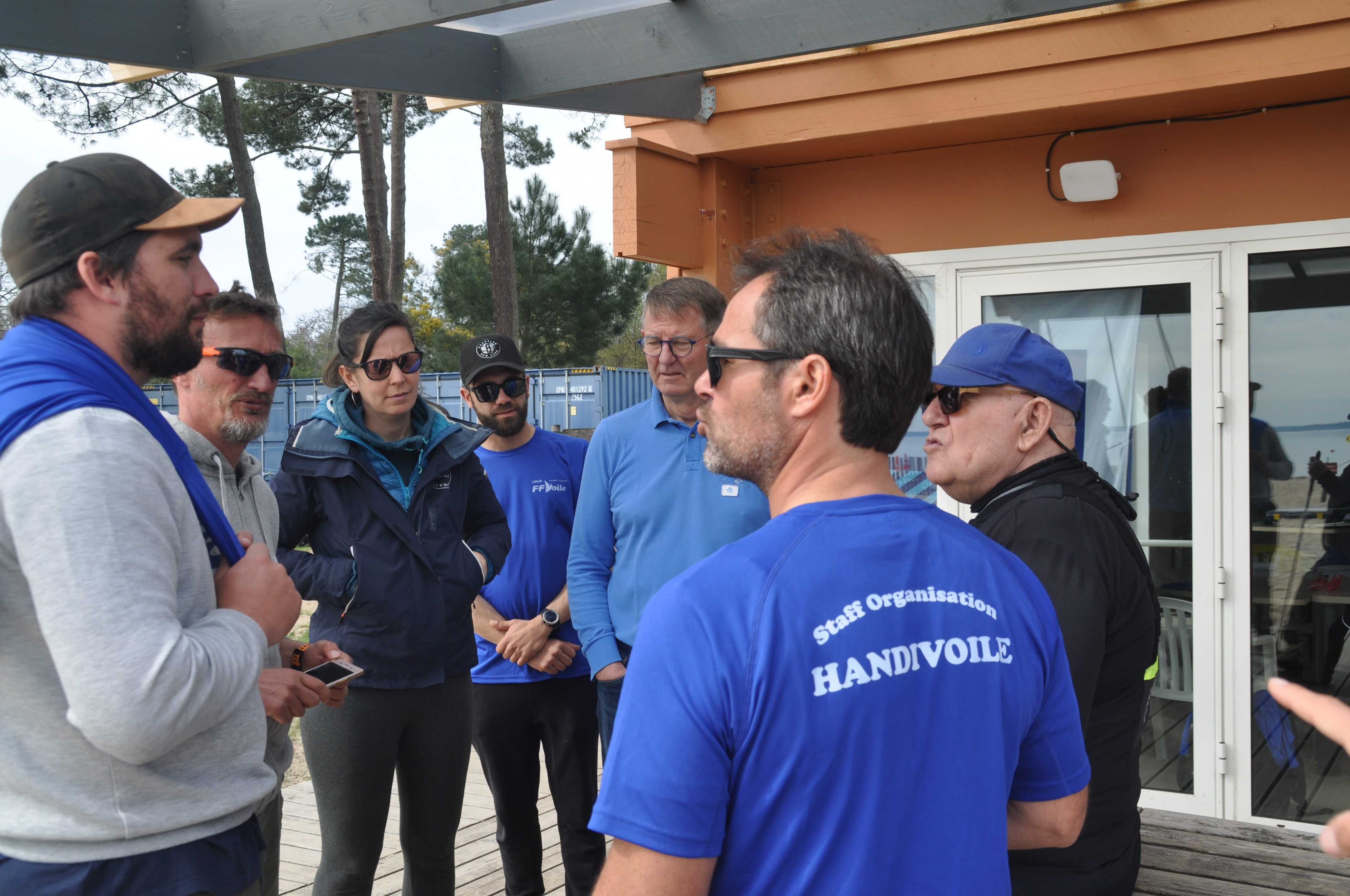 Un groupe de bénévoles et moniteurs discutent devant un club